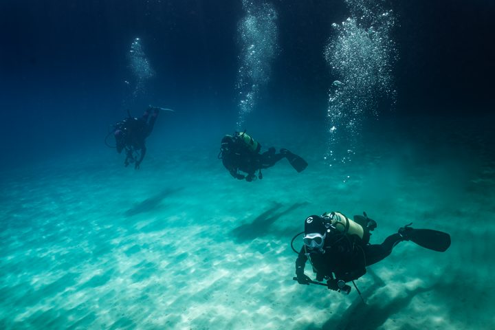 Gruppo di subacquei in immersione con scia di bolle, Mar Mediterraneo